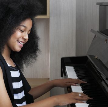 Young pretty beautiful American African girl playing piano.